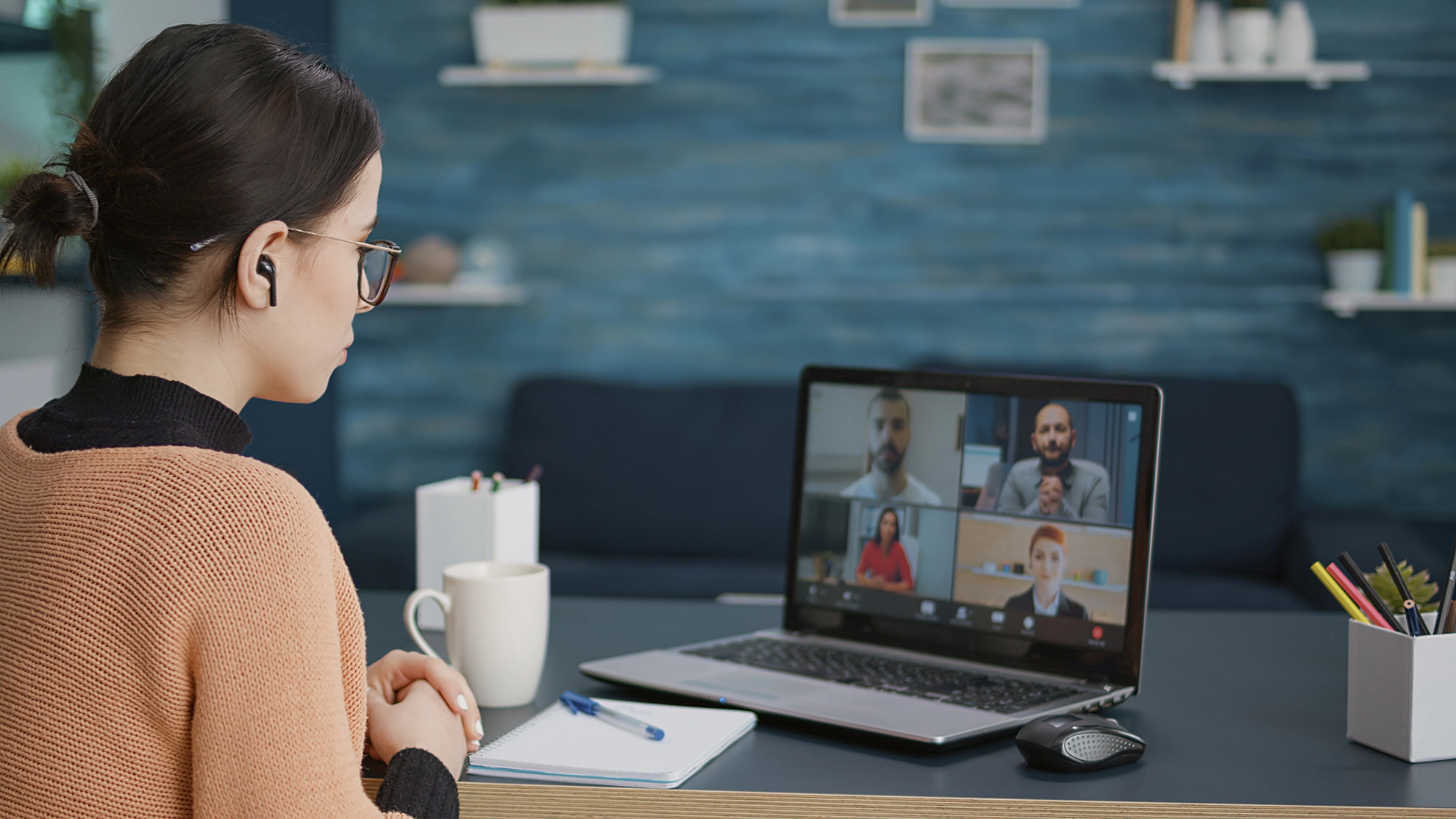 woman having an online conference call with four people on the laptop screen