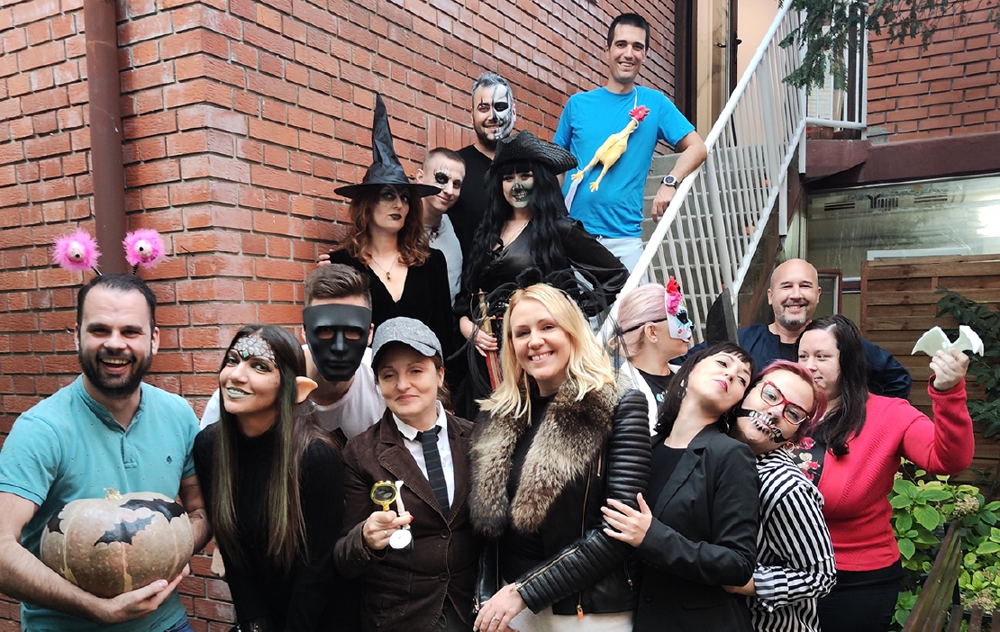Alas employees smiling and laughing at the office party, wearing halloween costumes.