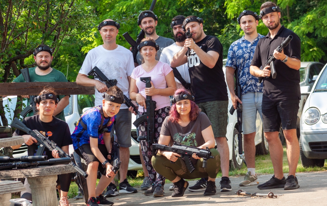 Company employees and a kid posing in nature, dressed in laser tag geer.